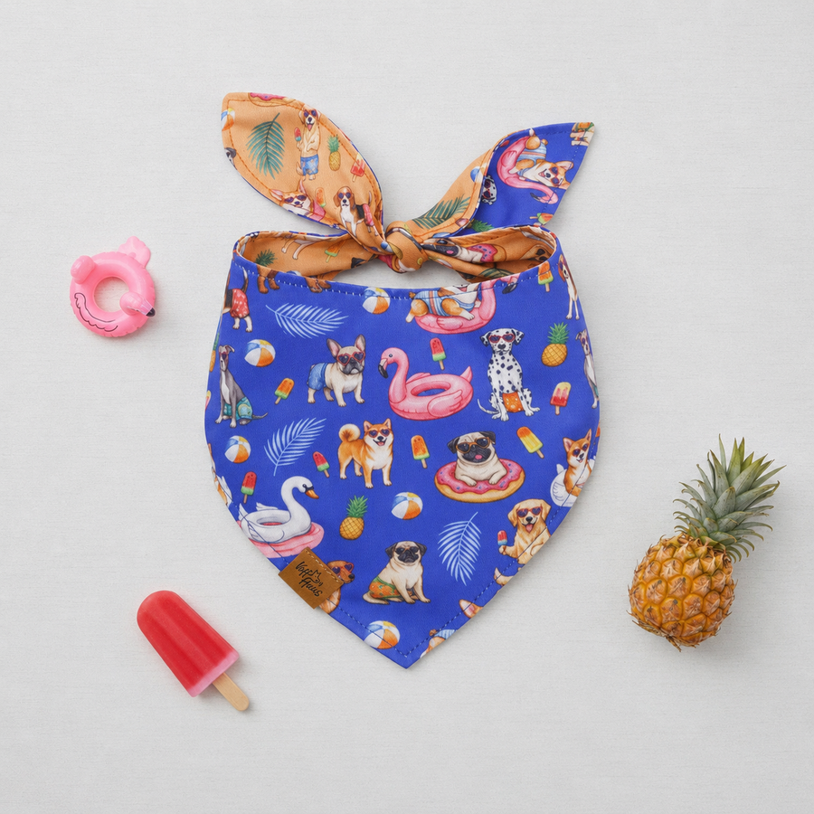 The Pool Pawty reversible dog bandana tied flat, royal blue side with poolside pups, beside a pineapple and popsicle