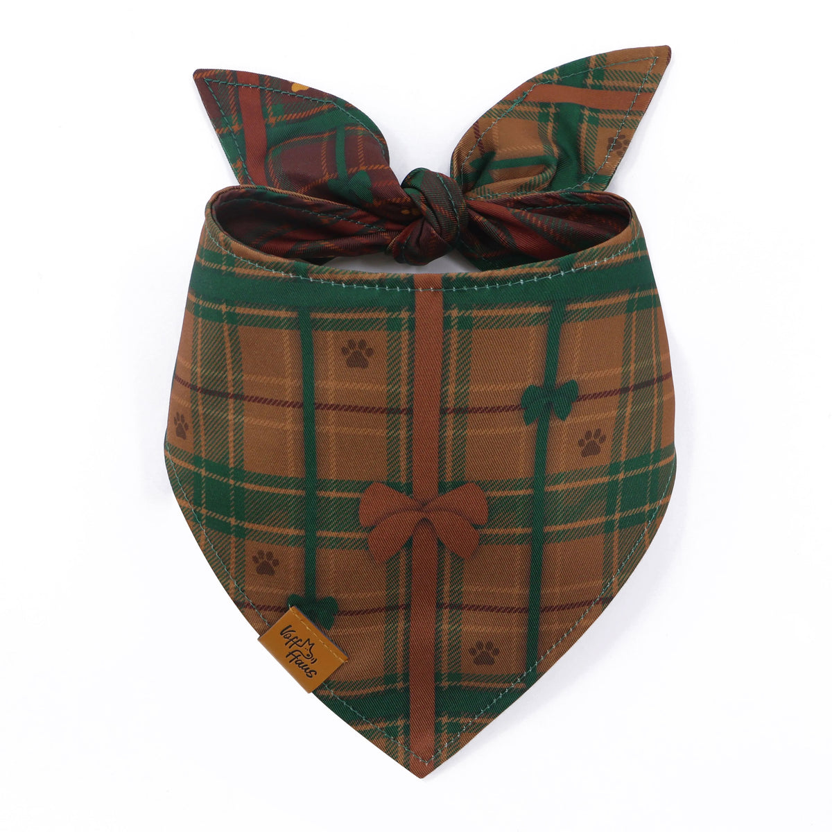 The Bark The Halls reversible dog bandana tied and laid flat, showing the chestnut plaid side with a bow and paw prints